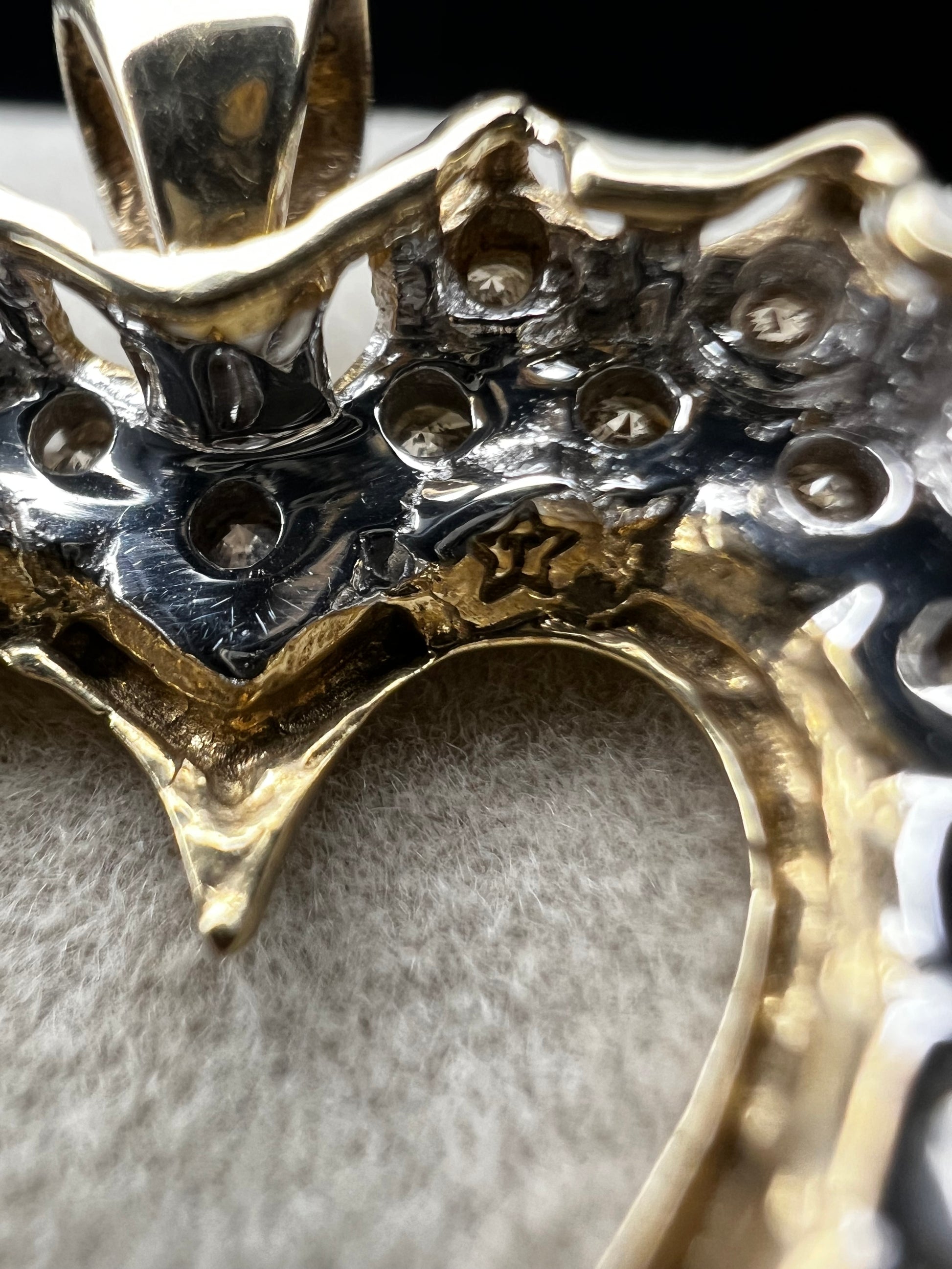 This heart-shaped pendant is crafted with 10 karat yellow gold with a bright white finish around the top to accentuate dazzling natural diamonds that cover the face of this piece.