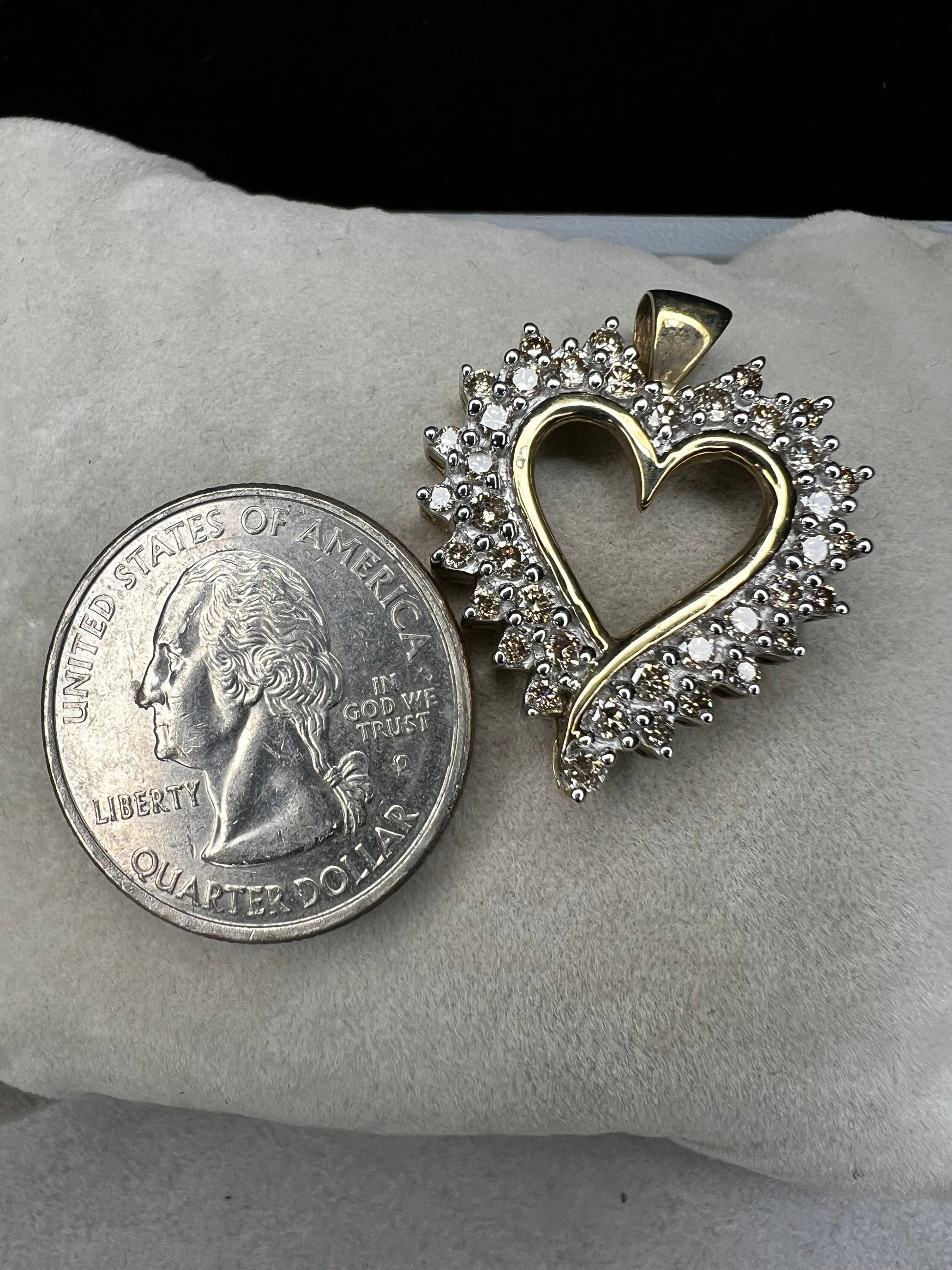 This heart-shaped pendant is crafted with 10 karat yellow gold with a bright white finish around the top to accentuate dazzling natural diamonds that cover the face of this piece.