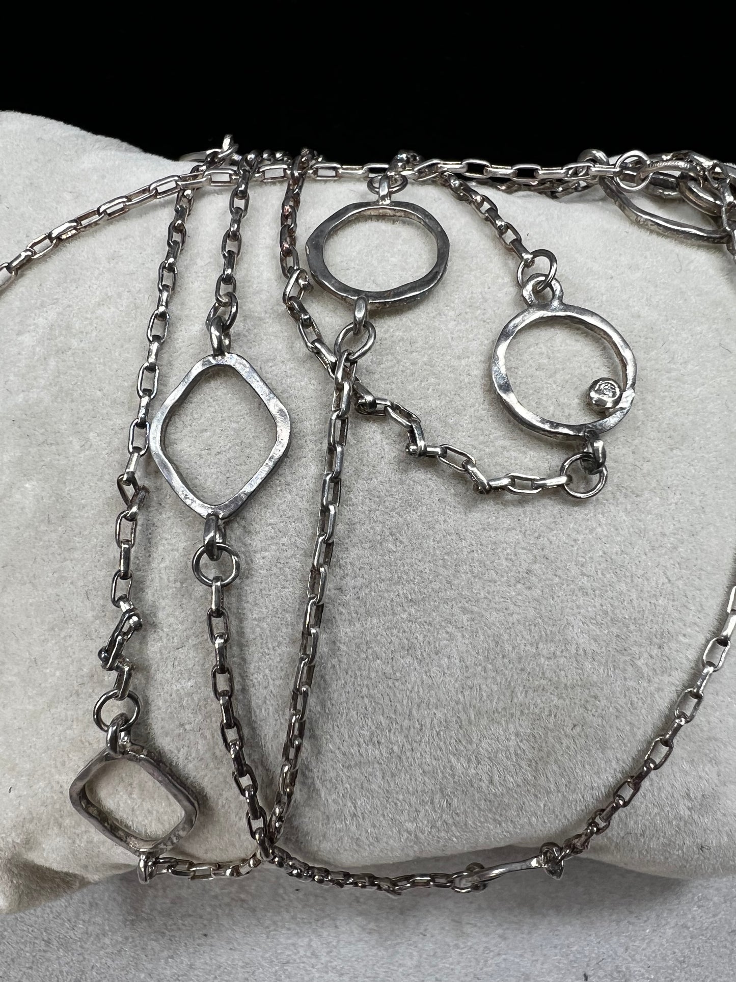 This long sterling silver necklace is designed with intermittent geometric links along the length of the chain. Two of those large links feature a small diamond for a touch of flash in the light. At 34 inches, this can be wrapped twice for a layered look, or it can be worn long. Made by Silpada.