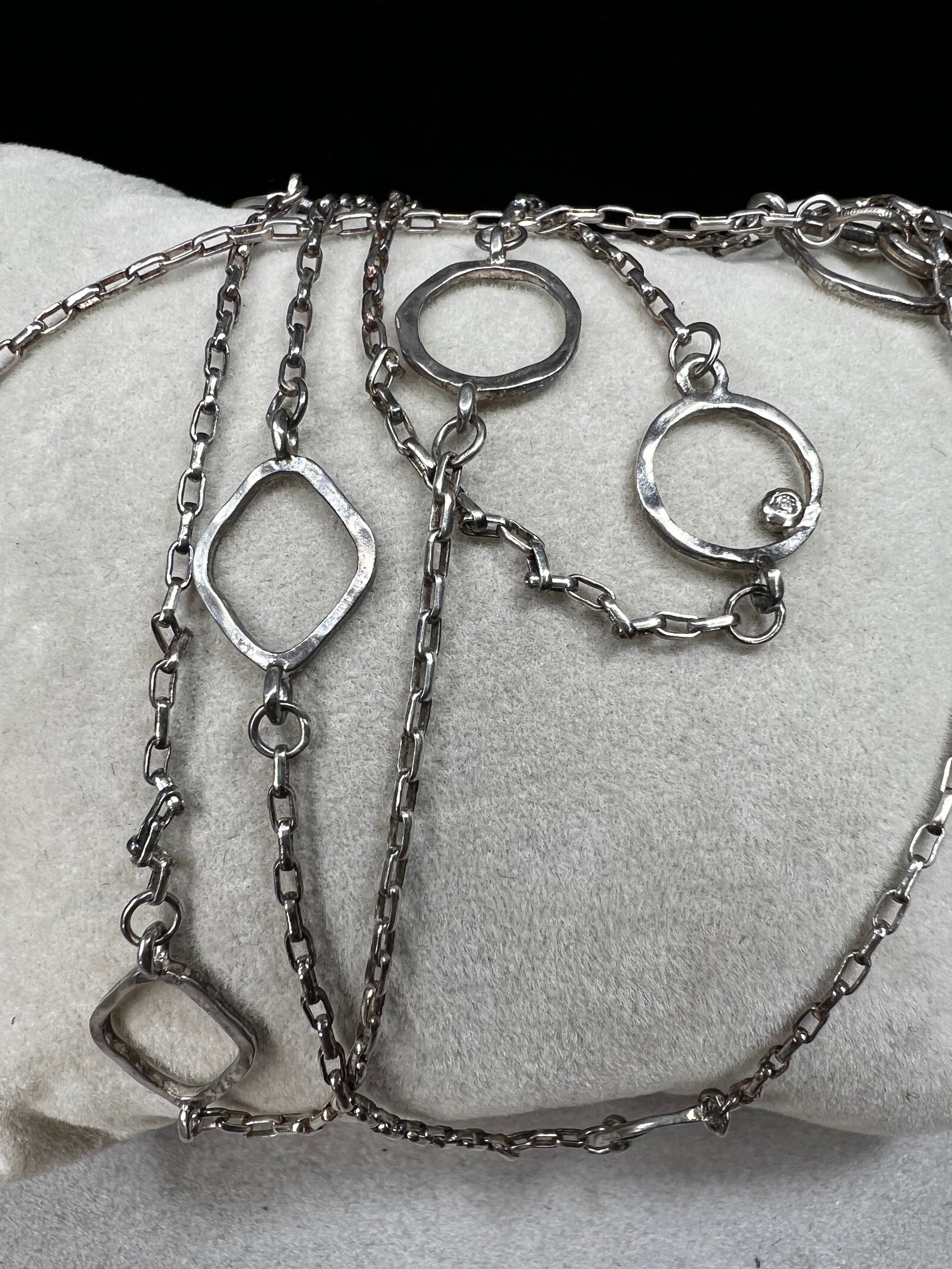 This long sterling silver necklace is designed with intermittent geometric links along the length of the chain. Two of those large links feature a small diamond for a touch of flash in the light. At 34 inches, this can be wrapped twice for a layered look, or it can be worn long. Made by Silpada.