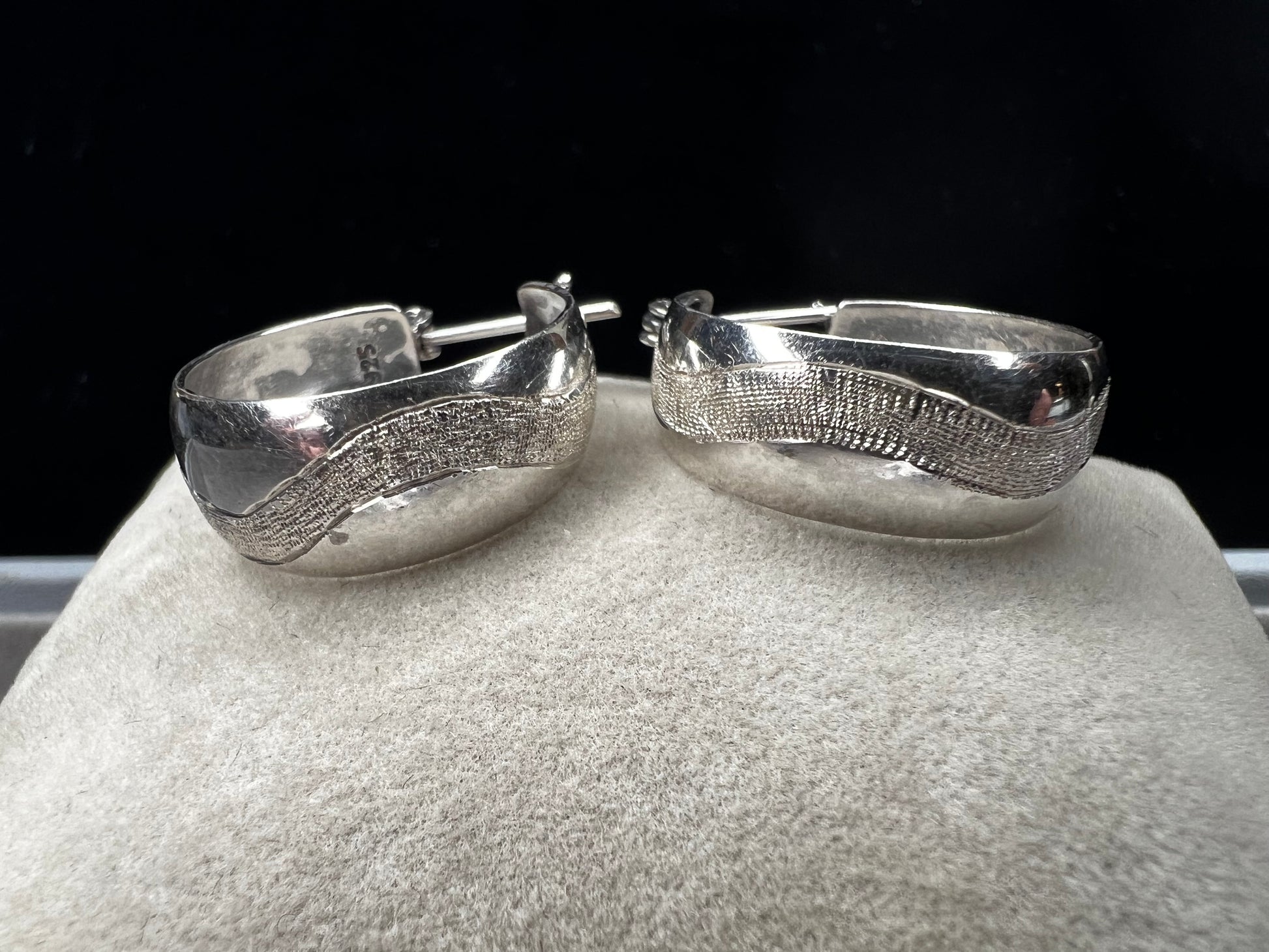 This vintage pair of sterling silver hoop earrings feature an etched design that resembles a snake wrapping around each earring.