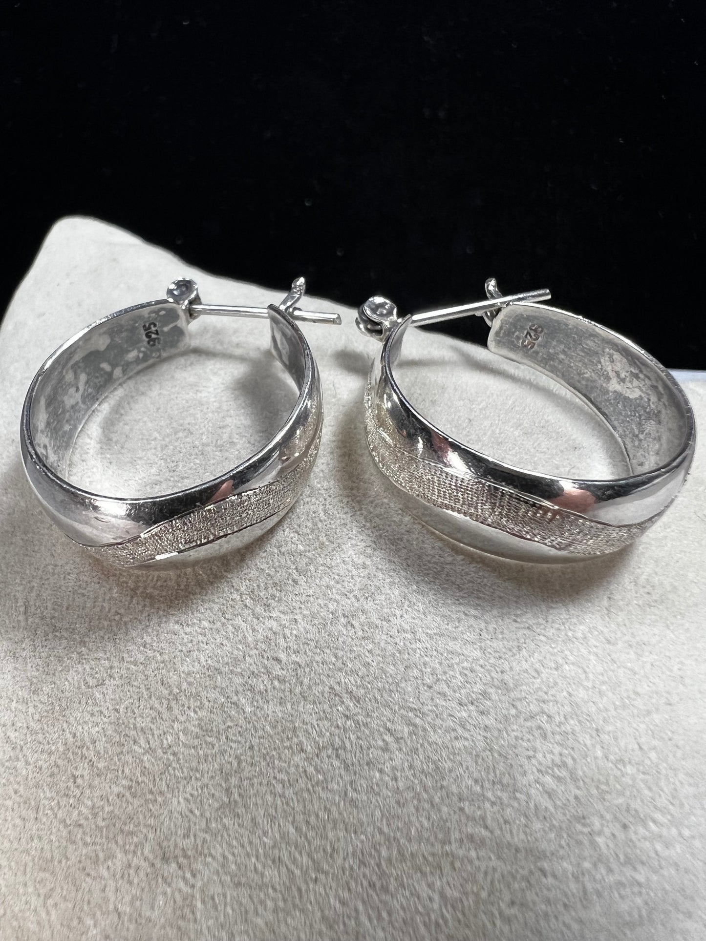 This vintage pair of sterling silver hoop earrings feature an etched design that resembles a snake wrapping around each earring.