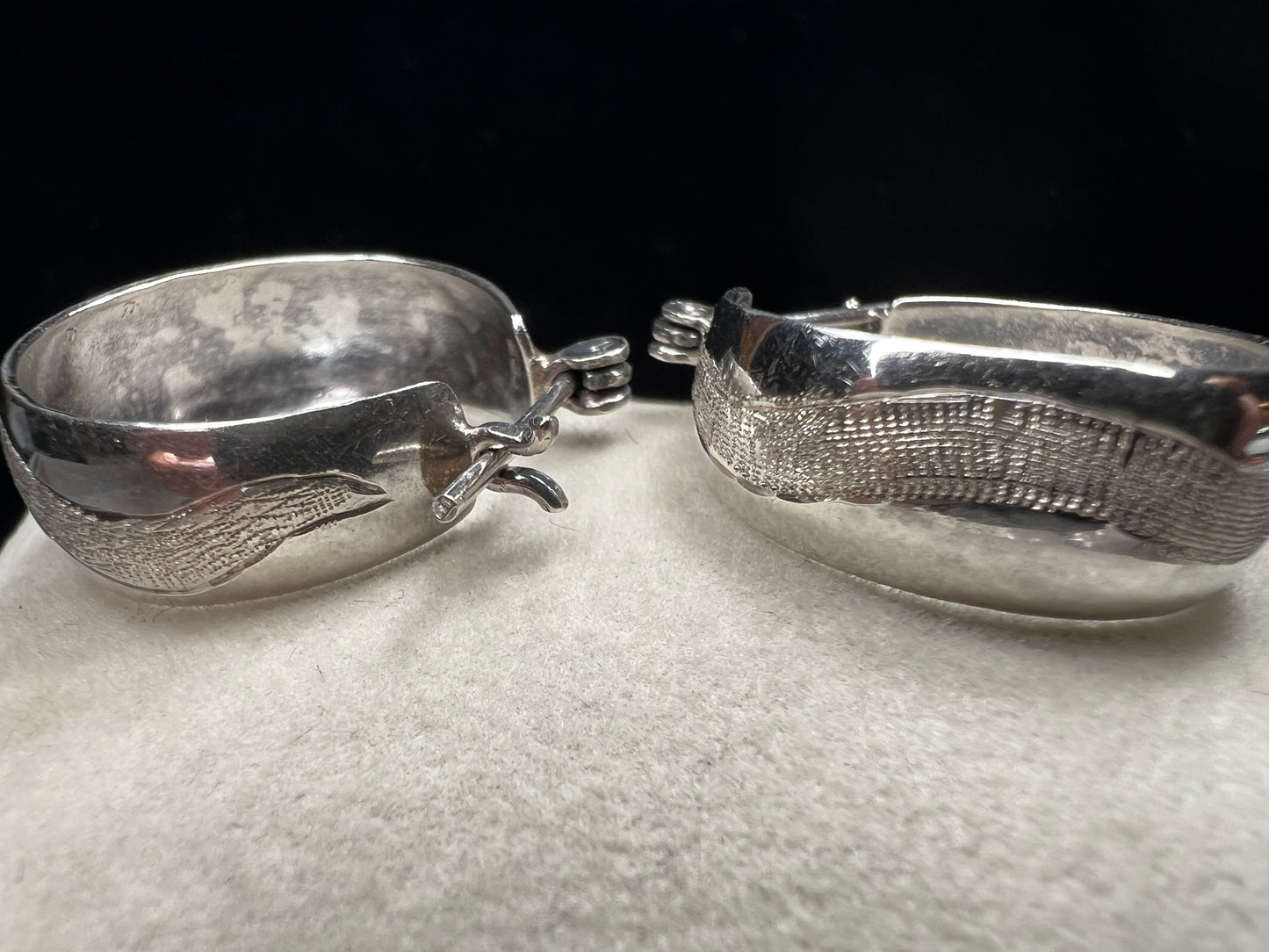 This vintage pair of sterling silver hoop earrings feature an etched design that resembles a snake wrapping around each earring.