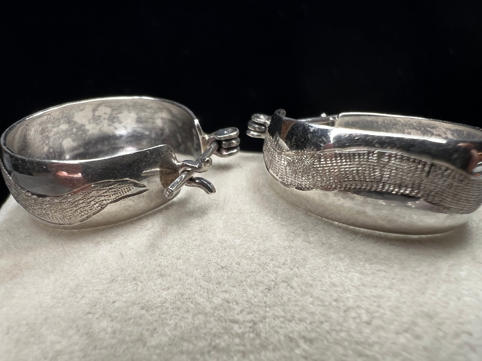 This vintage pair of sterling silver hoop earrings feature an etched design that resembles a snake wrapping around each earring.