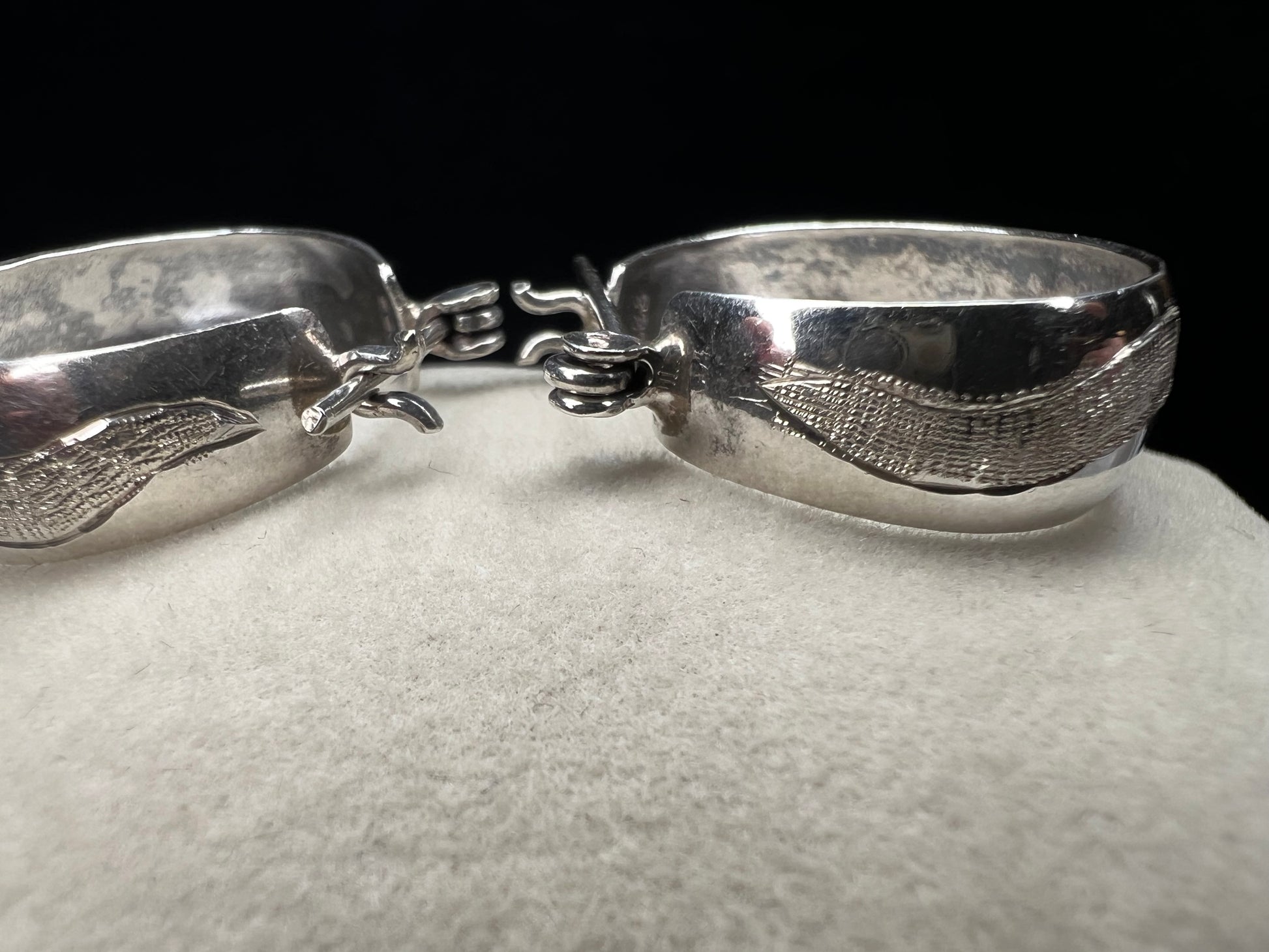 This vintage pair of sterling silver hoop earrings feature an etched design that resembles a snake wrapping around each earring.