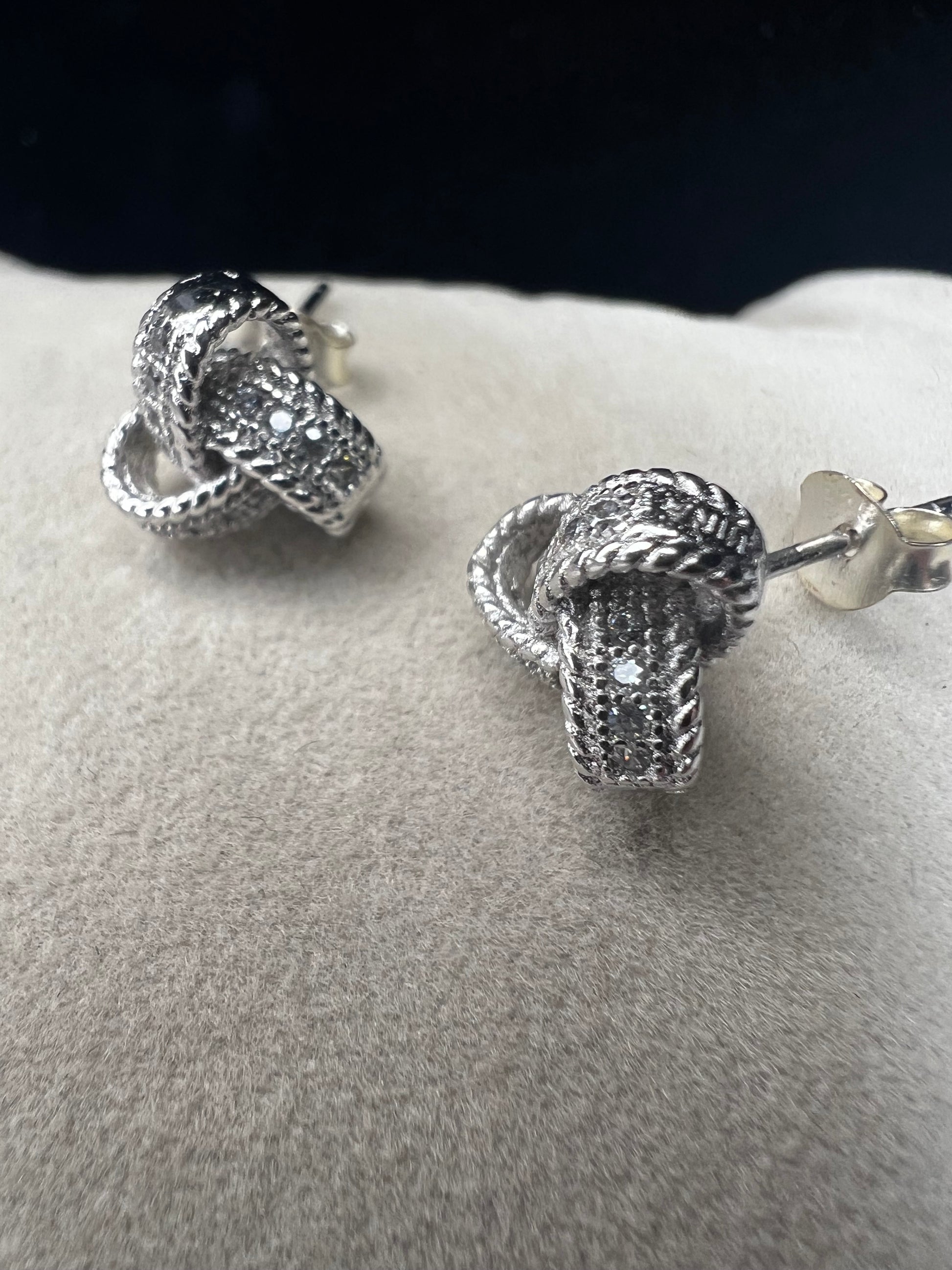 Sterling silver and diamond earrings. Perfect for a special event or just a night out. The diamonds are set along the knotted ribbon design, ready to catch just the right light for a little flash.